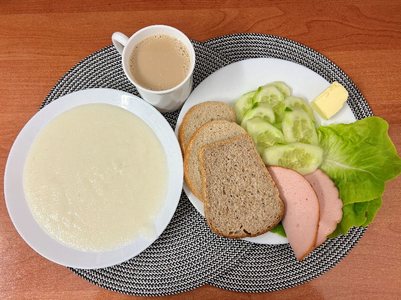 Na zdjęciu: Kasza manna na mleku, Kawa zbożowa z mlekiem, Chleb mieszany pszenno-żytni, Chleb Graham, Masło extra 82%, Filet zapiekany drobiowy, Ogórek świeży, ​​​​​​​Sałata zielona